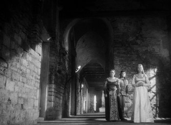Movie still from “Othello” (1951), directed by Orson Welles – A group of women standing next to each other; Wide shot, Low angle