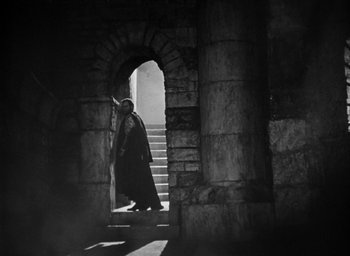 Movie still from “Othello” (1951), directed by Orson Welles – A man walking down the steps of an old building; Wide shot, Low angle