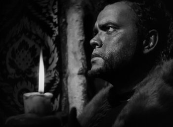 Movie still from “Othello” (1951), directed by Orson Welles – A black and white photo of a man looking at a candle; Close Up shot, Low angle