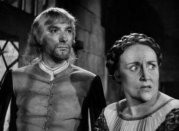 Movie still from “Othello” (1951), directed by Orson Welles – A black and white photo of a man and a woman; Medium shot, Over the shoulder angle