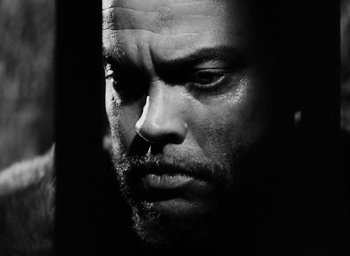 Movie still from “Othello” (1951), directed by Orson Welles – Black and white photograph of a man looking at the camera; Close Up shot, Low angle