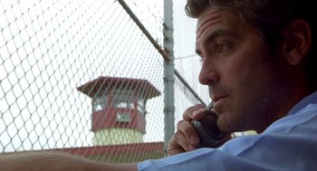 Movie still from “Out of Sight” (1998), directed by Steven Soderbergh – A man talking on a cell phone next to a fence; Close Up shot, Low angle