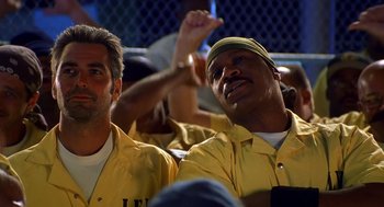 Movie still from “Out of Sight” (1998), directed by Steven Soderbergh – A couple of men sitting next to each other in a stadium; Close Up shot, Low angle