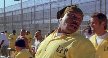 Movie still from “Out of Sight” (1998), directed by Steven Soderbergh – A man in a yellow prison uniform and a yellow hat; Medium shot, Low angle