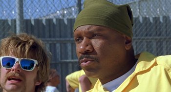 Movie still from “Out of Sight” (1998), directed by Steven Soderbergh – A person wearing a yellow shirt and a green hat; Close Up shot, Low angle