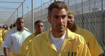 Movie still from “Out of Sight” (1998), directed by Steven Soderbergh – A group of men standing next to each other in front of a chain link fence; Close Up shot, Over the shoulder angle