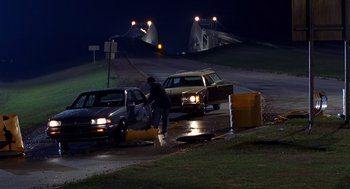 Movie still from “Out of Sight” (1998), directed by Steven Soderbergh – A man pushing a car on the side of the road; Wide shot, High angle