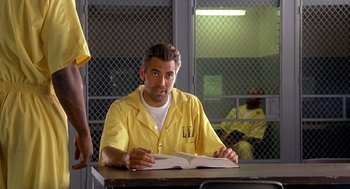 Movie still from “Out of Sight” (1998), directed by Steven Soderbergh – A man sitting at a table in a jail cell; Medium shot, Over the shoulder angle