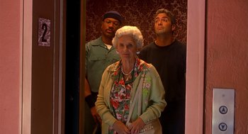 Movie still from “Out of Sight” (1998), directed by Steven Soderbergh – An older woman standing between two men in front of a door; Medium shot, Low angle