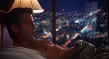 Movie still from “Out of Sight” (1998), directed by Steven Soderbergh – A man sitting on a bed looking out a window at night; Medium shot, High angle