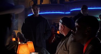 Movie still from “Out of Sight” (1998), directed by Steven Soderbergh – A man standing in front of another man in front of a crowd; Medium shot, Over the shoulder angle