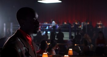 Movie still from “Out of Sight” (1998), directed by Steven Soderbergh – A man standing in front of a group of people in a room; Medium shot, Over the shoulder angle
