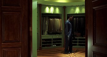 Movie still from “Out of Sight” (1998), directed by Steven Soderbergh – A man standing in front of a closet in a suit room; Wide shot, High angle
