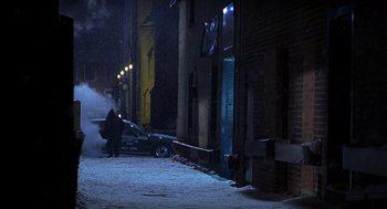 Movie still from “Out of Sight” (1998), directed by Steven Soderbergh – A person standing next to a car on a snowy street at night; Extreme Wide shot, High angle