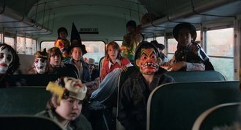 Movie still from “Out of the Blue” (1980), directed by Dennis Hopper – A group of people on a school bus with masks on; Wide shot, High angle