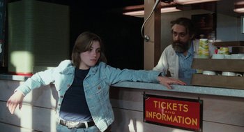 Movie still from “Out of the Blue” (1980), directed by Dennis Hopper – A young woman standing in front of a ticket counter; Medium shot, Low angle