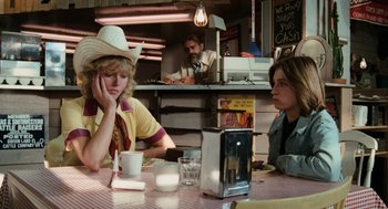 Movie still from “Out of the Blue” (1980), directed by Dennis Hopper – Two people sitting at a table in a restaurant; Medium shot, Over the shoulder angle