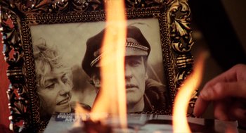 Movie still from “Out of the Blue” (1980), directed by Dennis Hopper – A picture of a man in a military uniform is in front of a fire; Extreme Close Up shot, Over the shoulder angle