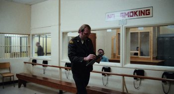 Movie still from “Out of the Blue” (1980), directed by Dennis Hopper – A man in a military uniform looking at his cell phone; Medium shot, Over the shoulder angle