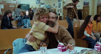 Movie still from “Out of the Blue” (1980), directed by Dennis Hopper – A man and a woman hugging at a table in a restaurant; Medium shot, Over the shoulder angle