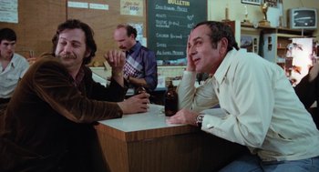 Movie still from “Out of the Blue” (1980), directed by Dennis Hopper – A group of men sitting at a table drinking beer; Medium shot, High angle