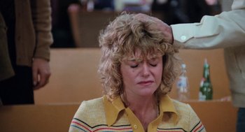 Movie still from “Out of the Blue” (1980), directed by Dennis Hopper – A person sitting in front of a table; Close Up shot, Over the shoulder angle