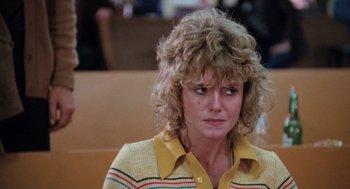 Movie still from “Out of the Blue” (1980), directed by Dennis Hopper – A person sitting in front of a table; Close Up shot, Low angle