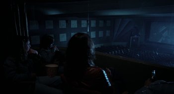 Movie still from “Out of the Blue” (1980), directed by Dennis Hopper – Two people sitting in a dark room at night; Wide shot, High angle