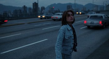 Movie still from “Out of the Blue” (1980), directed by Dennis Hopper – A woman walking down the street at night; Medium shot, Low angle