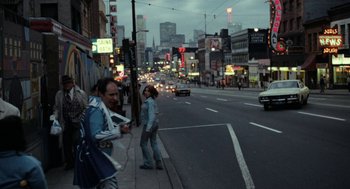 Movie still from “Out of the Blue” (1980), directed by Dennis Hopper – A man and a woman standing on the side of a road; Wide shot, High angle