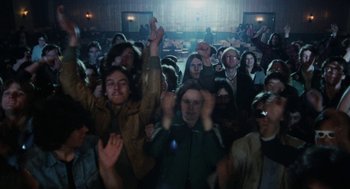 Movie still from “Out of the Blue” (1980), directed by Dennis Hopper – A group of people standing in front of a crowd; Wide shot, High angle