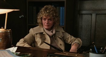 Movie still from “Out of the Blue” (1980), directed by Dennis Hopper – A woman sitting at a desk in a room; Medium shot, Over the shoulder angle