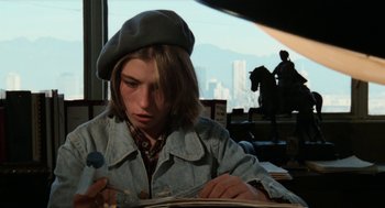 Movie still from “Out of the Blue” (1980), directed by Dennis Hopper – A person sitting at a table writing on a book; Medium shot, High angle