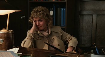 Movie still from “Out of the Blue” (1980), directed by Dennis Hopper – A woman sitting at a desk in front of a book case; Medium shot, High angle