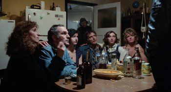 Movie still from “Out of the Blue” (1980), directed by Dennis Hopper – A group of people sitting at a table with drinks; Medium shot, High angle