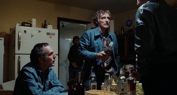 Movie still from “Out of the Blue” (1980), directed by Dennis Hopper – A group of people sitting at a table with food; Medium shot, Low angle