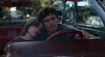 Movie still from “Out of the Blue” (1980), directed by Dennis Hopper – A man and a girl sitting in the driver's seat of a car; Close Up shot, High angle