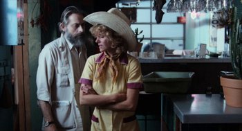 Movie still from “Out of the Blue” (1980), directed by Dennis Hopper – A man and a woman standing next to each other in front of a counter; Medium shot, Over the shoulder angle
