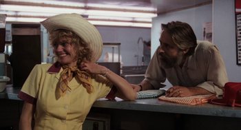 Movie still from “Out of the Blue” (1980), directed by Dennis Hopper – A woman wearing a hat and a man with a beard; Medium shot, Over the shoulder angle