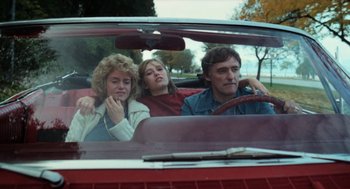 Movie still from “Out of the Blue” (1980), directed by Dennis Hopper – A group of people sitting in the back seat of a car; Medium shot, Low angle