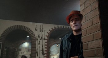 Movie still from “Out of the Blue” (1980), directed by Dennis Hopper – A man wearing a hat leaning against a brick wall; Close Up shot, Low angle