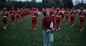 Movie still from “Out of the Blue” (1980), directed by Dennis Hopper – A woman standing in front of a group of people; Wide shot, High angle