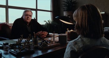 Movie still from “Out of the Blue” (1980), directed by Dennis Hopper – Two people sitting at a table talking to each other; Medium shot, Over the shoulder angle