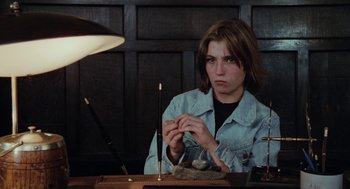 Movie still from “Out of the Blue” (1980), directed by Dennis Hopper – A woman sitting at a table with a pen and a pencil; Medium shot, High angle
