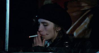 Movie still from “Out of the Blue” (1980), directed by Dennis Hopper – A person smoking a cigarette while wearing a black hat; Close Up shot, Over the shoulder angle