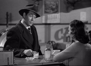 Movie still from “Out of the Past” (1947), directed by Jacques Tourneur – A man and a woman sitting at a table with drinks; Medium shot, Over the shoulder angle