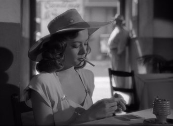Movie still from “Out of the Past” (1947), directed by Jacques Tourneur – A black and white photo of a woman smoking a cigarette; Close Up shot, Over the shoulder angle