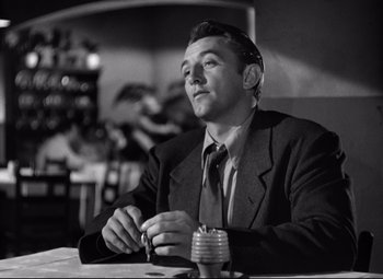 Movie still from “Out of the Past” (1947), directed by Jacques Tourneur – A black and white photo of a man sitting at a table; Close Up shot, Low angle