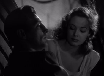 Movie still from “Out of the Past” (1947), directed by Jacques Tourneur – A man and a woman sitting next to each other in a room; Close Up shot, Over the shoulder angle