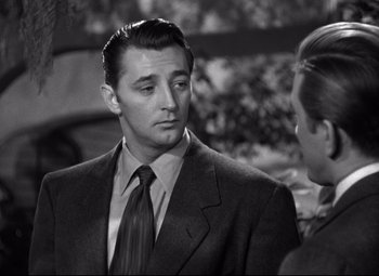 Movie still from “Out of the Past” (1947), directed by Jacques Tourneur – A black and white photo of a man wearing a suit and tie; Close Up shot, Over the shoulder angle